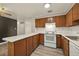 Bright kitchen featuring wood cabinets, white appliances, and light countertops at 6432 Zephyr St, Arvada, CO 80004