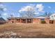 Spacious backyard view showcasing a well-maintained lawn and brick home with some snow remnants at 7310 S Sheridan Ct, Littleton, CO 80128