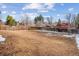 Expansive backyard enclosed by a wooden fence, featuring a mix of dry leaves and snow remnants at 7310 S Sheridan Ct, Littleton, CO 80128