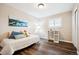 Well-lit bedroom showcasing wood-look flooring, a cozy daybed, a stylish side table, and a serene painting at 7310 S Sheridan Ct, Littleton, CO 80128