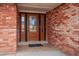 Close-up of the decorative wooden front door with glass sidelights and a brick facade, creating a welcoming entrance at 7310 S Sheridan Ct, Littleton, CO 80128