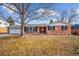 Charming brick home featuring an attached two-car garage and a beautifully landscaped front yard beneath a sunny, blue sky at 7310 S Sheridan Ct, Littleton, CO 80128