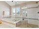 Bright bathroom featuring a glass enclosed shower, soaking tub, and window with shutter blinds at 15935 W 77Th Pl, Arvada, CO 80007