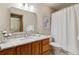 Bathroom featuring wood cabinets, granite counters, and a shower behind a curtain at 15935 W 77Th Pl, Arvada, CO 80007