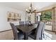 Elegant dining room with a dark wood table, six gray upholstered chairs, and a stylish chandelier at 15935 W 77Th Pl, Arvada, CO 80007
