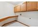 Clean laundry room features tile flooring, wood trim, upper cabinets, and a built-in folding counter at 15935 W 77Th Pl, Arvada, CO 80007