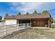 Outbuilding featuring a brown roof, wood siding, white fencing, and mature trees at 15935 W 77Th Pl, Arvada, CO 80007