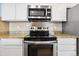 Close-up of a well-equipped kitchen with stainless steel appliances and tiled backsplash at 7234 E 38Th Ave, Denver, CO 80207