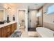 Modern bathroom featuring a soaking tub, glass shower, and sleek wood vanity with white countertop at 3188 W 28Th Ave, Denver, CO 80211