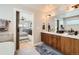 Bright bathroom featuring wood vanity with white countertop, large mirror, and doorway to the main bedroom at 3188 W 28Th Ave, Denver, CO 80211