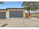 Two-car garage with gray doors and a wooden access gate on a concrete driveway and mature trees nearby at 3188 W 28Th Ave, Denver, CO 80211