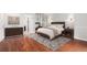 Bedroom featuring hardwood floors, a bed with nightstands and dresser, all elegantly styled at 3210 S Oneida Way, Denver, CO 80224