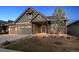 Inviting home with a manicured lawn, stone accents, a two-car garage and covered porch with chairs at 2882 Heron Lakes Pkwy, Berthoud, CO 80513
