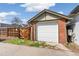 View of a detached brick garage with a white door and fenced yard at 2826 Quitman St, Denver, CO 80212