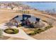 Stunning aerial view of brick home with a circular driveway, lush landscaping and lake views at 2366 Shoreside Dr, Berthoud, CO 80513