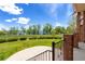 Landscaped backyard featuring an iron fence, lush lawn, mature trees and water views at 2366 Shoreside Dr, Berthoud, CO 80513