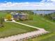 A home with a long drive boasts lake views, lush green lawns, and mature landscaping at 2366 Shoreside Dr, Berthoud, CO 80513