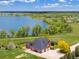 Aerial front exterior of brick home boasts mature trees and landscaping and a lake view in the background at 2366 Shoreside Dr, Berthoud, CO 80513