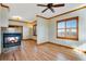 Cozy living area featuring a fireplace, wood floors, a ceiling fan, and natural light at 2366 Shoreside Dr, Berthoud, CO 80513