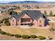 Aerial view of a large brick home showcasing an upper balcony and a lower patio at 2366 Shoreside Dr, Berthoud, CO 80513