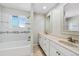 Bright bathroom featuring dual sinks, and a tub with tiled walls and mosaic accents at 7746 S Harrison Cir, Centennial, CO 80122