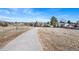 Long driveway leads to the house on a wide lot with mature trees and blue skies at 7746 S Harrison Cir, Centennial, CO 80122