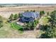 Back view of a two-story home with a deck and patio, beautifully landscaped yard, mature trees and green grass at 9563 Red Primrose St, Franktown, CO 80116