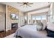 Sunlit primary bedroom featuring a stone fireplace, TV, deck access and beautiful views at 9563 Red Primrose St, Franktown, CO 80116