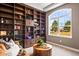 Home office with custom built-in bookshelves, comfortable seating, and a large window with scenic views at 9563 Red Primrose St, Franktown, CO 80116