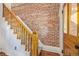 Elegant staircase featuring exposed brick wall and classic wood banister and door at 2543 Stout St, Denver, CO 80205