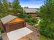 Wide aerial view of a brown home and a two-car garage surrounded by many trees at 776 Hilltop Rd, Palmer Lake, CO 80133