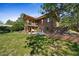 Expansive backyard with lush green grass, mature trees, a wooden deck, and a bubbling hot tub for ultimate relaxation at 776 Hilltop Rd, Palmer Lake, CO 80133
