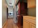 Convenient hallway laundry setup with stacked washer and dryer next to wooden cabinets and hardwood floors leading to open area at 776 Hilltop Rd, Palmer Lake, CO 80133