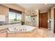 Bright bathroom featuring marble tile, soaking tub, glass shower, and a window at 16519 E Hialeah Dr, Centennial, CO 80015