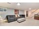 Finished basement with gray sofa, beige ottoman, and colorful wall art near stairs at 6930 S Delaware St, Littleton, CO 80120