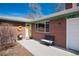 Charming front yard featuring a brick facade, bright yellow door, and a welcoming bench at 6930 S Delaware St, Littleton, CO 80120