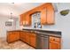 A kitchen featuring a stainless steel dishwasher, a double sink, and oak cabinetry at 6930 S Delaware St, Littleton, CO 80120