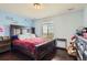 Comfortable bedroom features a large window, dark wood furniture, and bright red bedding at 7658 S Country Club Pkwy, Aurora, CO 80016