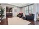 Bright living room offering a dark cabinet with glass doors, neutral paint, and plush chairs with ottomans at 7658 S Country Club Pkwy, Aurora, CO 80016