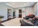 Comfortable living room featuring dark leather seating, plush white carpet, stylish shelving, and tray ceilings at 7658 S Country Club Pkwy, Aurora, CO 80016