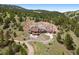 Aerial view of luxury home nestled in wooded hills featuring stone terraces and ample parking at 21609 Clarence Ln, Golden, CO 80401