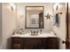 Charming powder room with dark wood vanity, stone countertop, and beach-themed decor at 21609 Clarence Ln, Golden, CO 80401