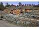 Backyard of the house showcasing a stone patio, string lights, and natural rock landscaping at 21609 Clarence Ln, Golden, CO 80401