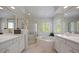 Bright bathroom featuring a soaking tub, glass-enclosed shower, and dual vanities with white cabinets at 9278 E Aspen Hill Pl, Lone Tree, CO 80124