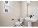 Modern bathroom with a pedestal sink, toilet, and window at 5936 N Lisbon St, Aurora, CO 80019