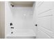 Bright bathroom featuring a white tiled shower-tub combo with black fixtures and a white three-panel door at 5936 N Lisbon St, Aurora, CO 80019
