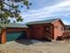 Charming red home featuring a green roof, matching green garage door, and rock landscaping at 656 County Road 72, Bailey, CO 80421