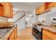 View of kitchen with laminate floors, oak cabinets, leading to the living room and a stairwell at 9925 W 20Th Ave # 17, Lakewood, CO 80215