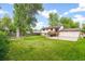 Large backyard featuring lush green grass, mature trees, a wooden fence, and a small garden area at 7503 Saulsbury St, Arvada, CO 80003