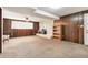 Spacious basement features a brick fireplace, wood paneling, neutral carpet, and bright window at 7503 Saulsbury St, Arvada, CO 80003